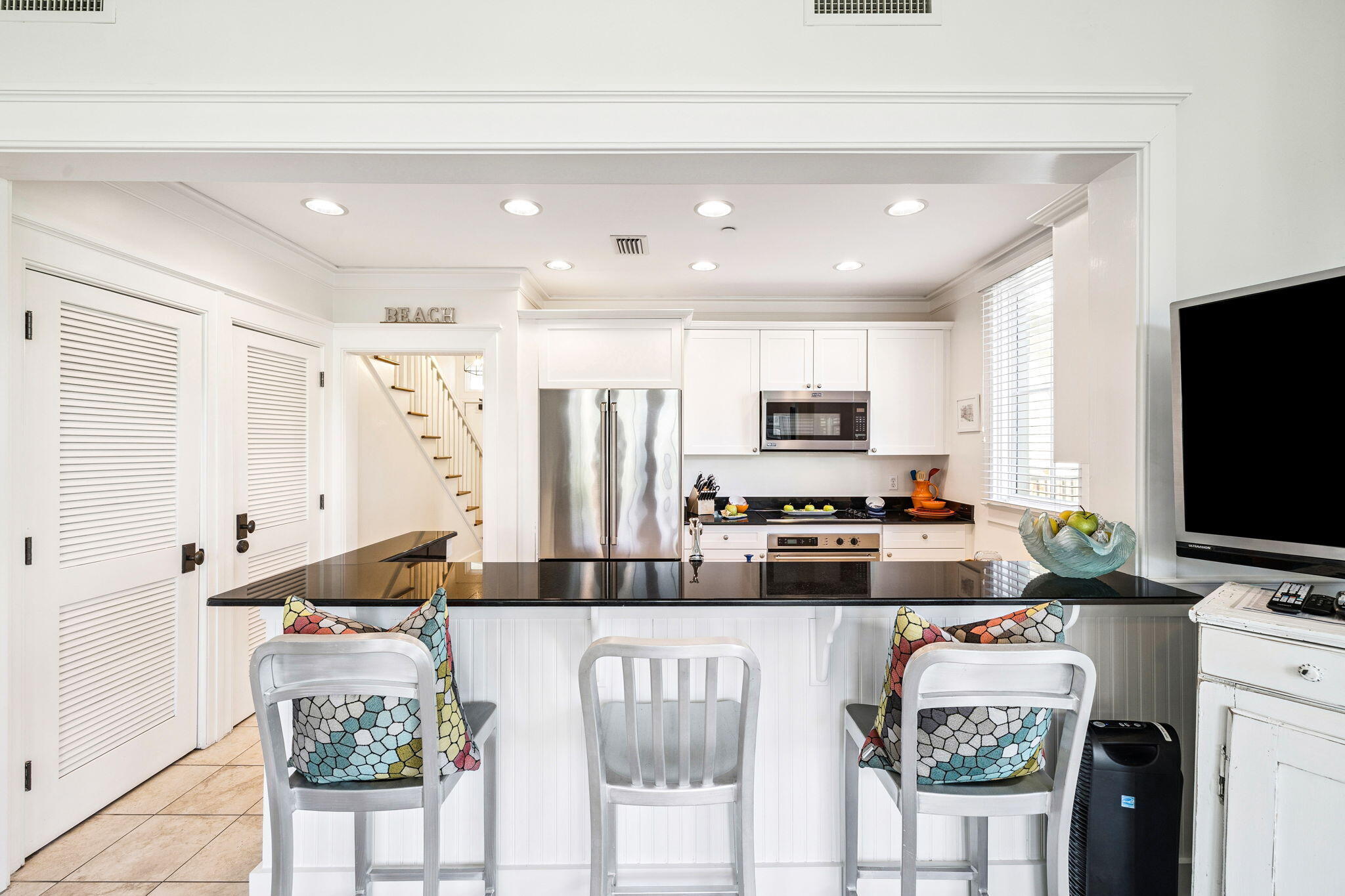 1640 East County Highway 30A, Unit 302 Santa Rosa Beach, FL 32459 - Photo 12 of 64 a kitchen with stainless steel appliances granite countertop a stove top oven a sink a refrigerator and white cabinets with wooden floor
