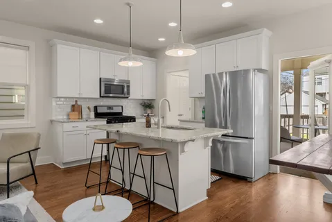 a kitchen with stainless steel appliances granite countertop a refrigerator a stove a sink a dining table and chairs with wooden floor