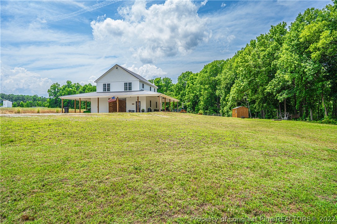 a view of a house with a big yard and large trees