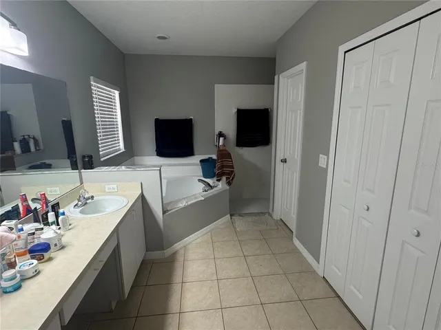 a en suite bathroom with a granite countertop sink a mirror and a bathtub
