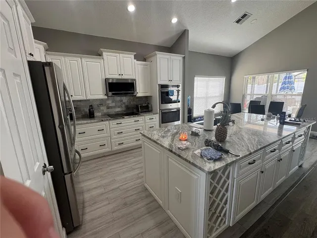 a kitchen with stainless steel appliances granite countertop a stove top oven a sink dishwasher a refrigerator and a refrigerator with wooden floor