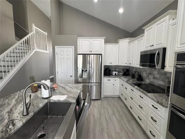 a kitchen with granite countertop a sink stove and refrigerator