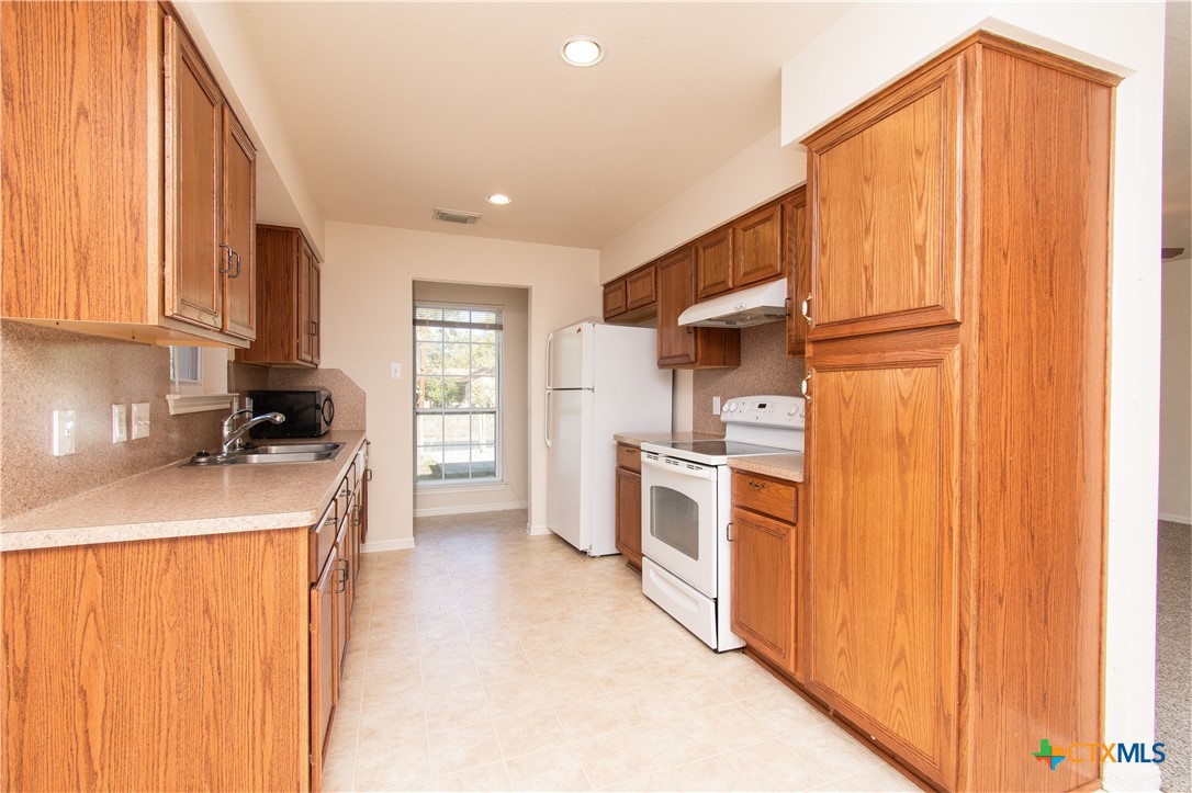 309 Ellis Street San Marcos, TX 78666 - Photo 7 of 18 a kitchen with a refrigerator a stove top oven a sink and dishwasher
