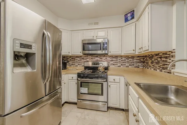 a kitchen with white cabinets and stainless steel appliances
