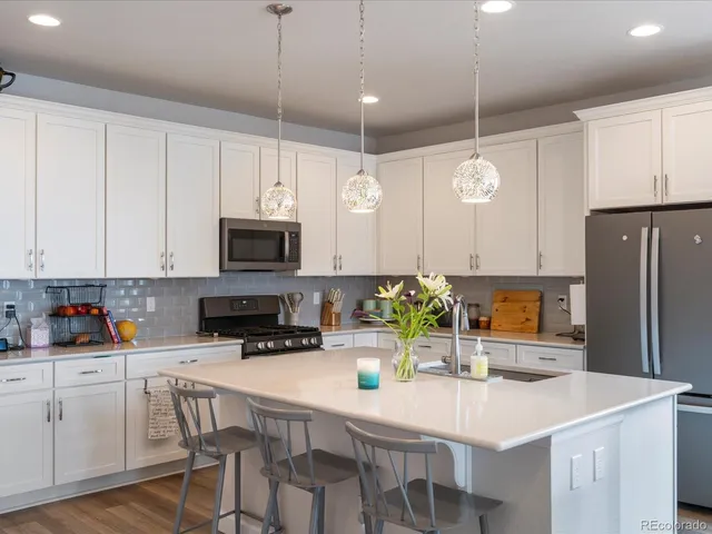 a kitchen with stainless steel appliances granite countertop a sink a stove a microwave a refrigerator a counter space and cabinets