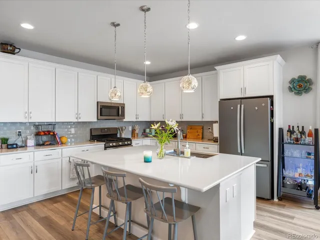 a kitchen with stainless steel appliances granite countertop a sink a stove a refrigerator cabinets and chairs