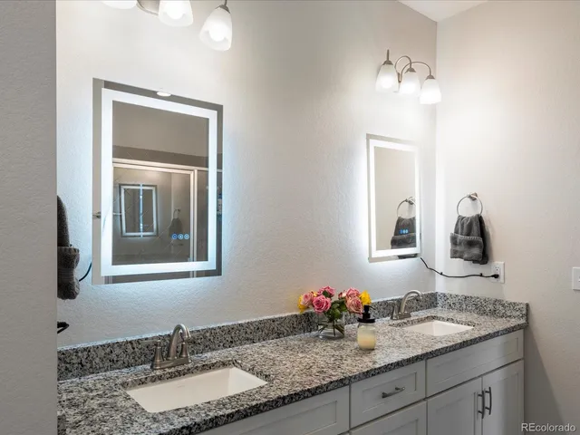 a bathroom with a granite countertop double sink and a mirror