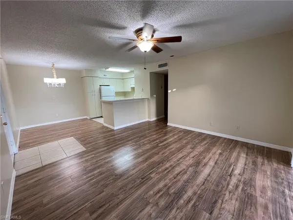 a view of an empty room and chandelier fan