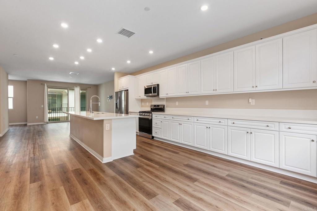 1771 Laurelwood Way Oceanside, CA 92056 - Photo 13 of 46 a kitchen with white cabinets and stainless steel appliances