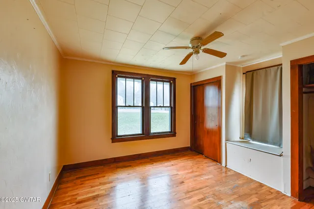 a view of an empty room with window and wooden floor