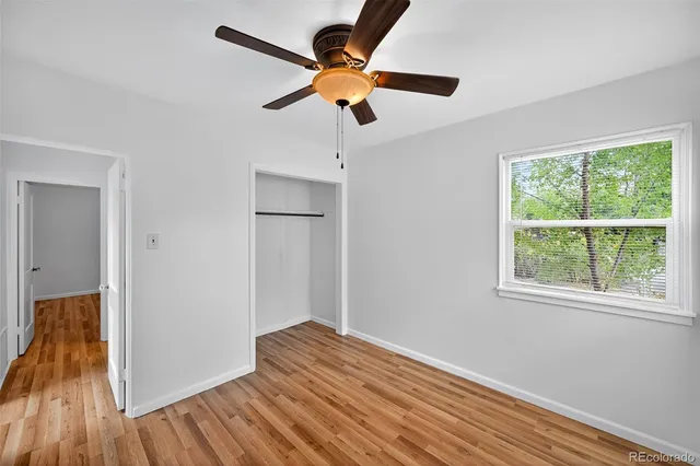 a view of empty room with wooden floor and fan