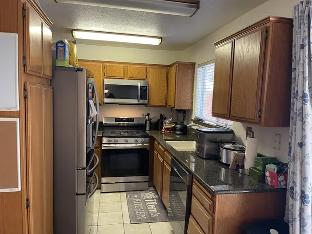 a kitchen with stainless steel appliances granite countertop a stove refrigerator and sink