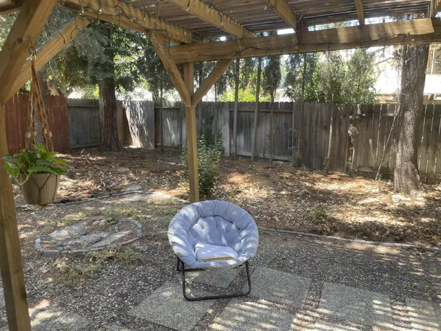 a view of a backyard with large tree and wooden fence