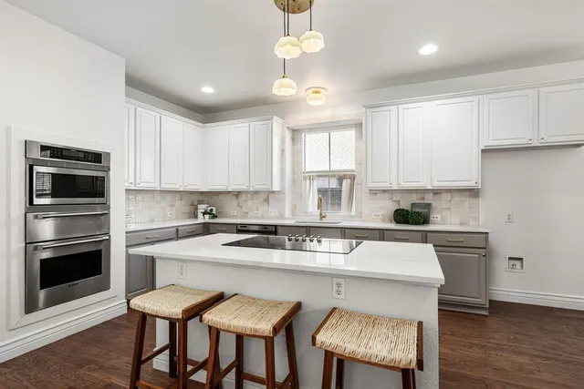 a kitchen with a dining table chairs stainless steel appliances and cabinets