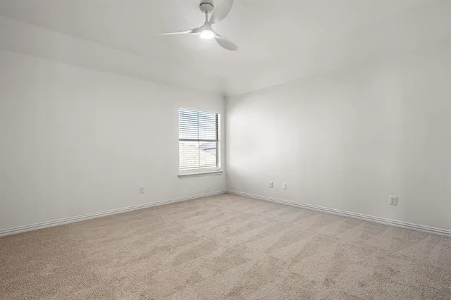 an empty room with a window and ceiling fan