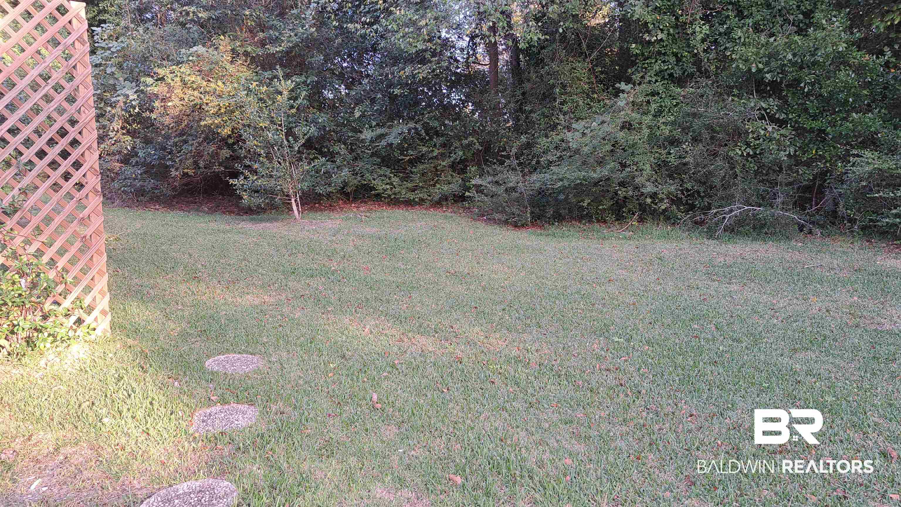 110 South Main Street Evergreen, AL 36401 - Photo 25 of 27 Expansive grassy yard featuring a wood lattice fence, stepping stones, and mature perimeter foliage