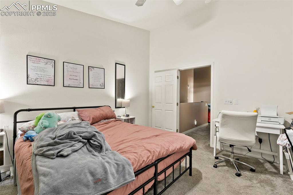 4573 Prestige Point Colorado Springs, CO 80906 - Photo 18 of 31 Bedroom featuring light carpet, ceiling fan, a desk, and a high ceiling