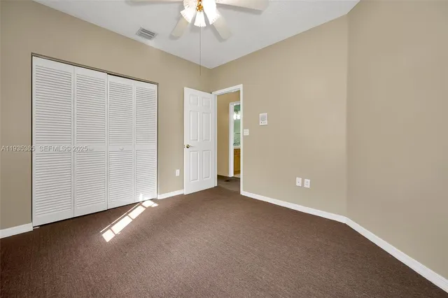 an empty room with a ceiling fan and window