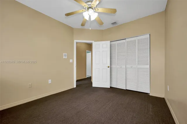 an empty room with closet and a chandelier fan