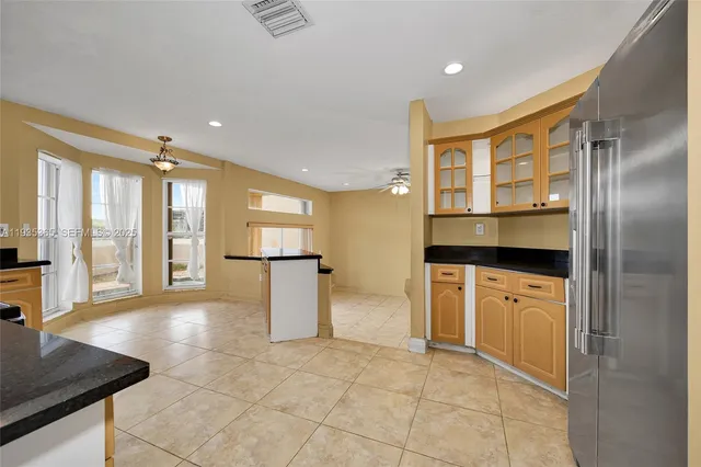 a view of a refrigerator in kitchen and an empty room
