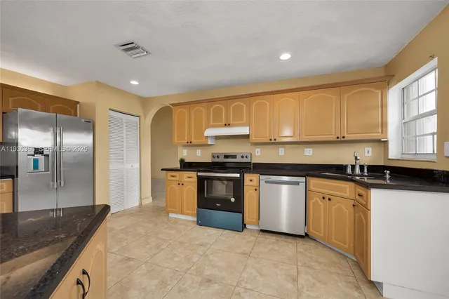 a kitchen with stainless steel appliances granite countertop a stove a sink and a refrigerator