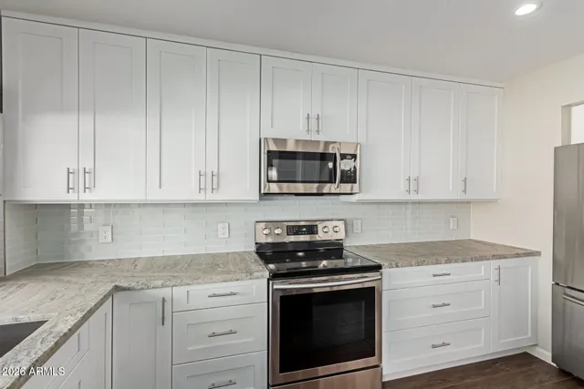 a kitchen with white cabinets and stainless steel appliances