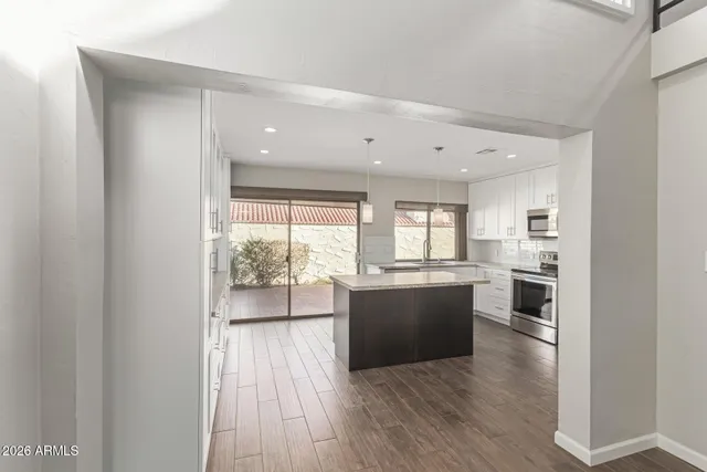 a living room with stainless steel appliances kitchen island wooden floor and large window