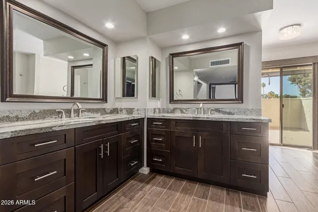 a bathroom with a granite countertop double vanity sink and mirror