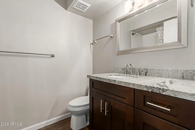 a bathroom with a granite countertop sink toilet and mirror