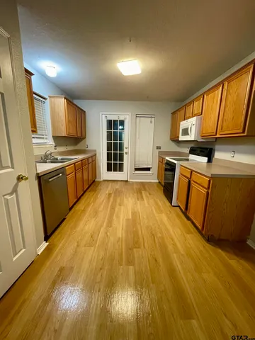 a kitchen with stainless steel appliances granite countertop a stove a sink dishwasher and a microwave with wooden floor