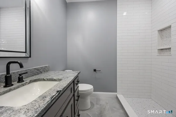 a bathroom with a granite countertop sink a toilet and shower