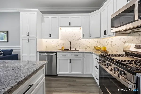 a kitchen with kitchen island granite countertop a sink cabinets and stainless steel appliances