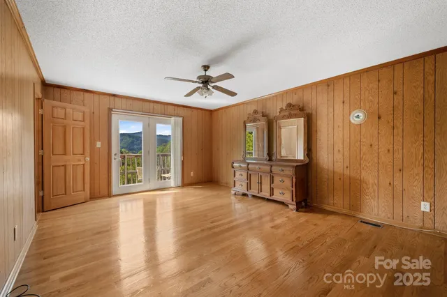 a view of empty room with wooden floor and fan