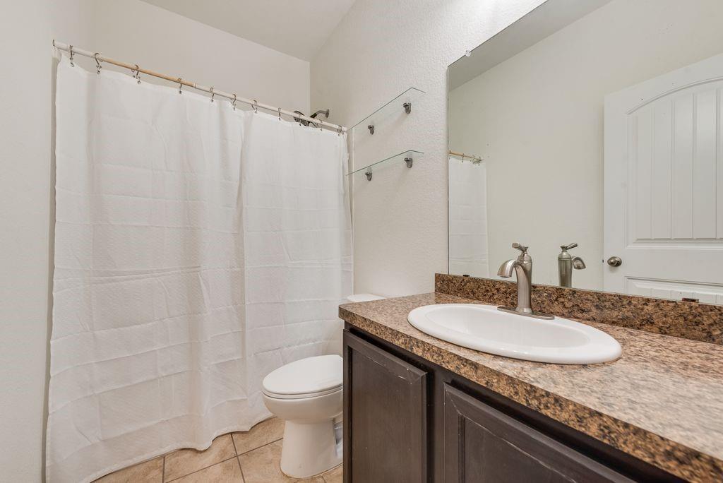 5117 Grayson Ridge Drive Fort Worth, TX 76179 - Photo 29 of 36 a bathroom with a granite countertop sink toilet and a mirror