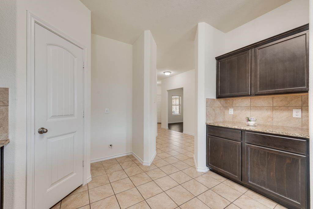 5117 Grayson Ridge Drive Fort Worth, TX 76179 - Photo 5 of 31 Kitchen with tile backsplash, a peninsula island, granite counters, stainless steel appliances, new microwave and dark wood finish cabinets.