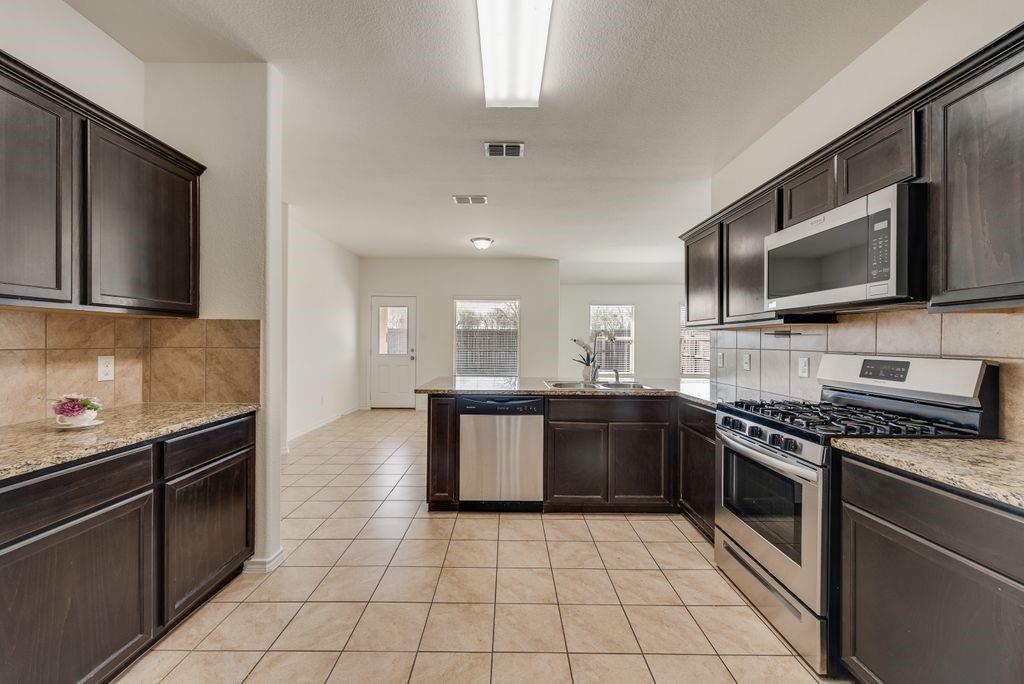 5117 Grayson Ridge Drive Fort Worth, TX 76179 - Photo 6 of 36 a large kitchen with a stove top oven and cabinets