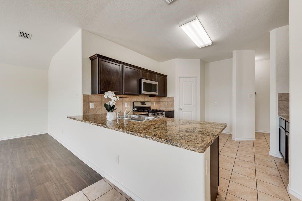 5117 Grayson Ridge Drive Fort Worth, TX 76179 - Photo 7 of 36 a kitchen with stainless steel appliances granite countertop a sink stove and refrigerator