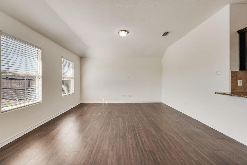5117 Grayson Ridge Drive Fort Worth, TX 76179 - Photo 9 of 31 Empty room with vaulted ceiling and dark wood finished floors