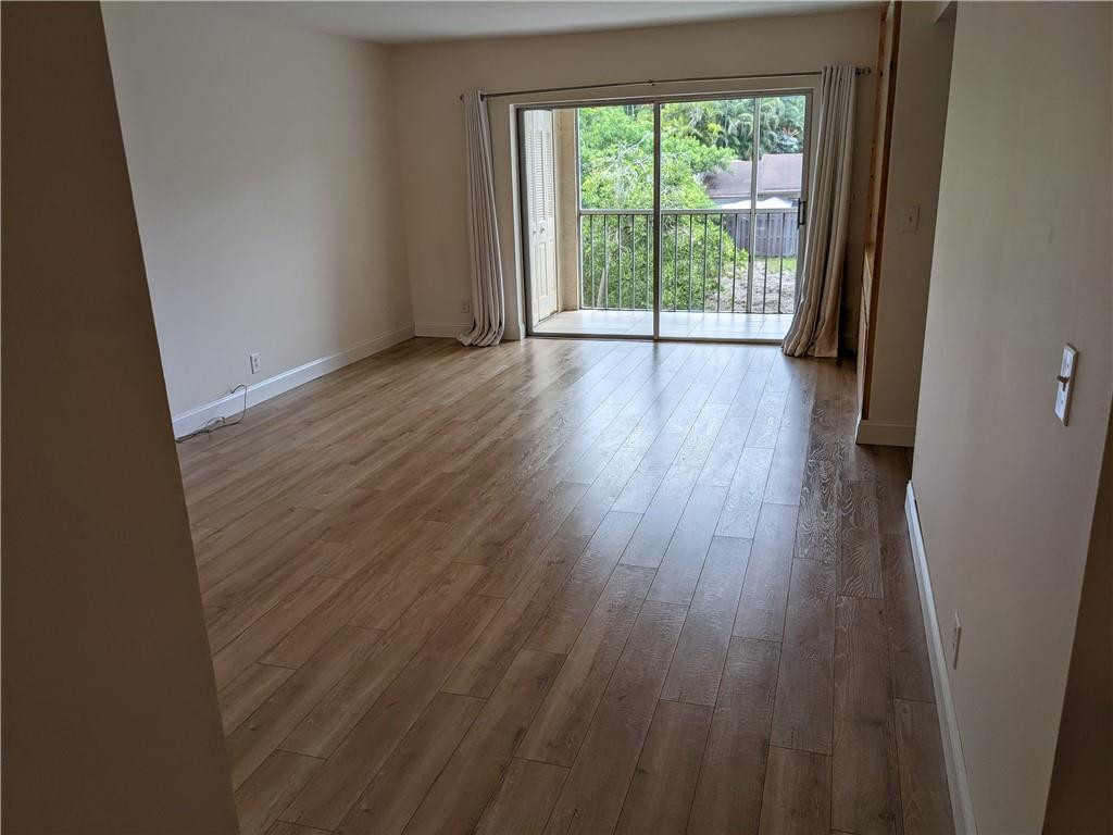 9280 Southwest 3rd Street, Unit 810 Boca Raton, FL 33428 - Photo 1 of 22 a view of an empty room with wooden floor and a window