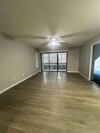 a view of an empty room with window and wooden floor