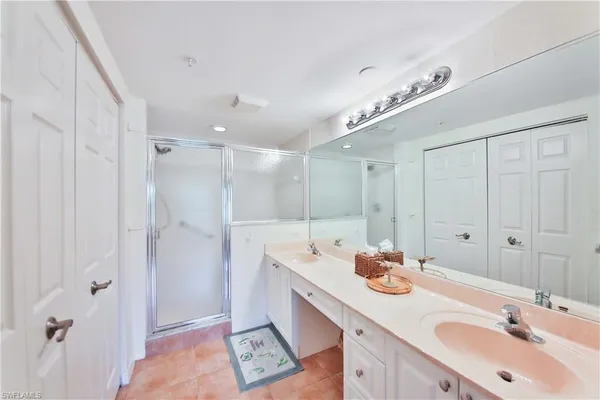 a bathroom with a sink double vanity granite tub shower and a mirror