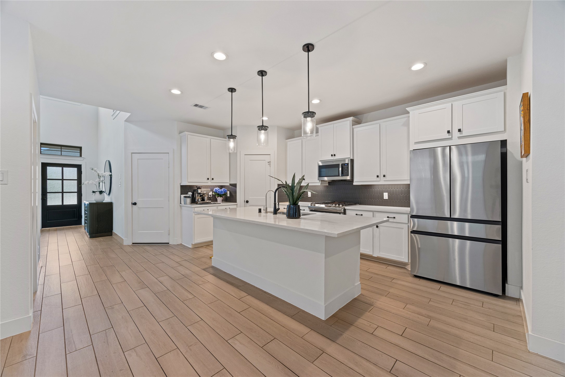 10636 Wild Chives Conroe, TX 77385 - Photo 7 of 29 a kitchen with stainless steel appliances granite countertop a refrigerator a sink dishwasher a oven and white cabinets with wooden floor
