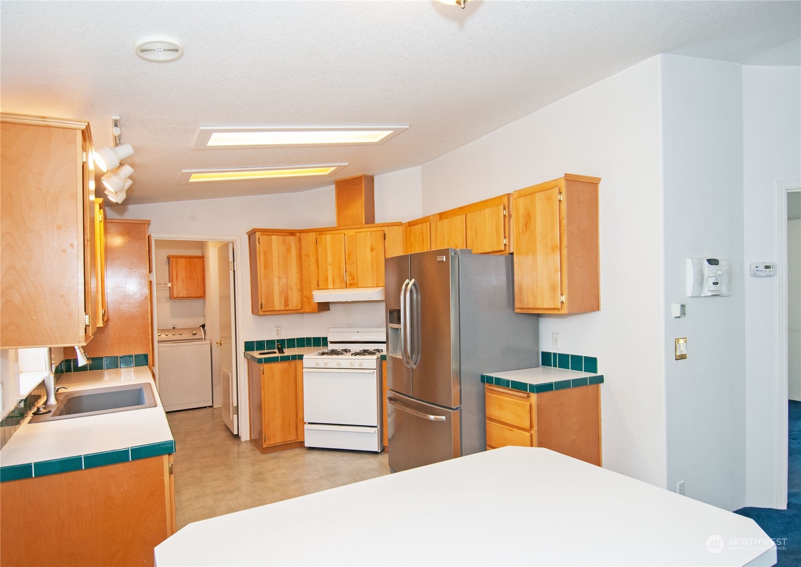 15400 Southeast 155th Place, Unit 12 Renton, WA 98058 - Photo 9 of 21 a kitchen with stainless steel appliances kitchen island granite countertop a refrigerator a stove and a sink