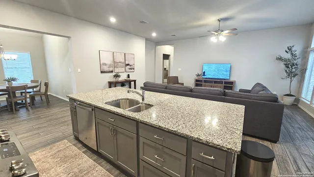 a kitchen with kitchen island granite countertop a sink a counter top space and living room view