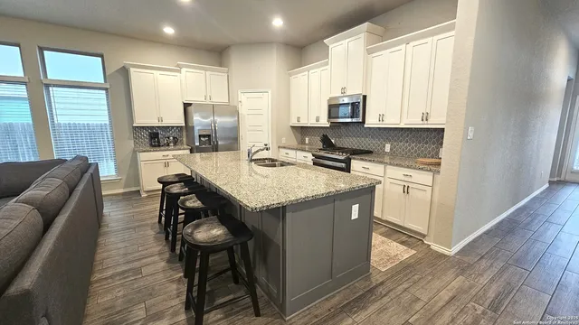a kitchen with stainless steel appliances granite countertop a table chairs sink refrigerator and cabinets