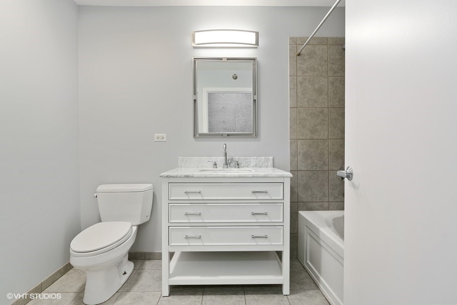 235 West Van Buren Street, Unit 4409 Chicago, IL 60607 - Photo 15 of 26 a bathroom with a toilet a sink and mirror