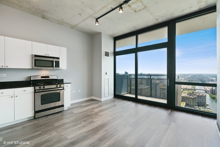 235 West Van Buren Street, Unit 4409 Chicago, IL 60607 - Photo 9 of 26 a view of a kitchen with a sink and dishwasher a stove top oven with wooden floor