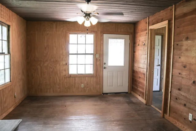 an empty room with windows and ceiling fan