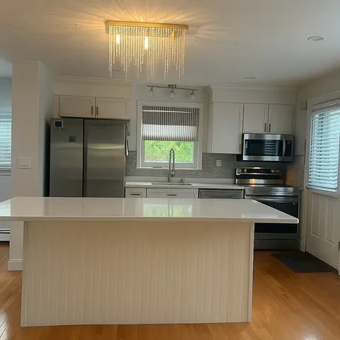 a kitchen with kitchen island granite countertop a stove a sink and a microwave