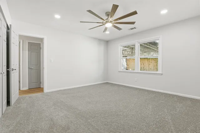 an empty room with windows and fan